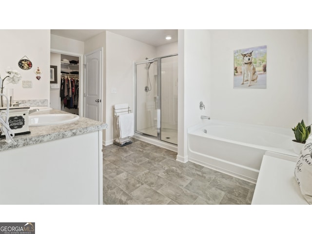 full bath featuring vanity, baseboards, a stall shower, a walk in closet, and a garden tub