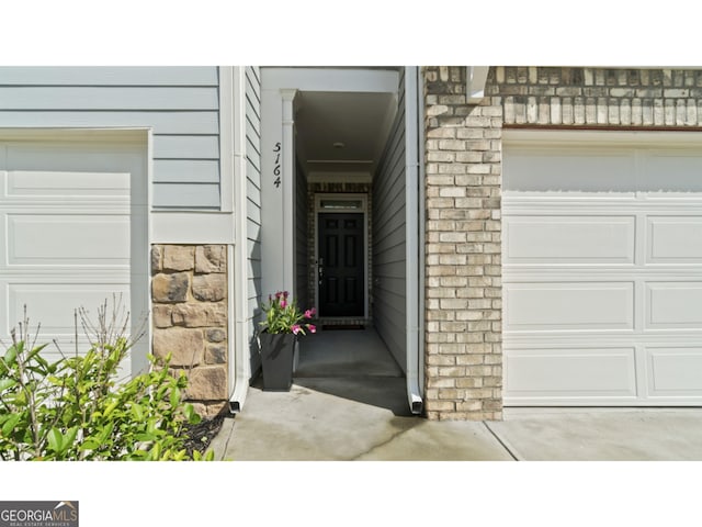 doorway to property featuring a garage and stone siding