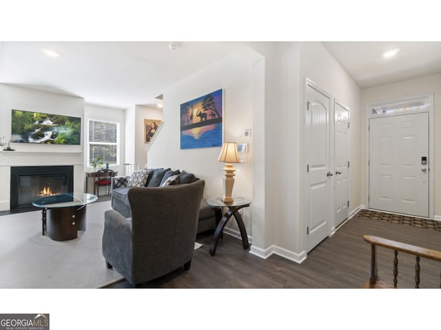 living room with recessed lighting, dark wood-style floors, baseboards, and a glass covered fireplace