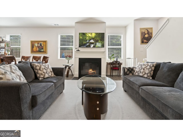 living room featuring a glass covered fireplace, wood finished floors, and visible vents