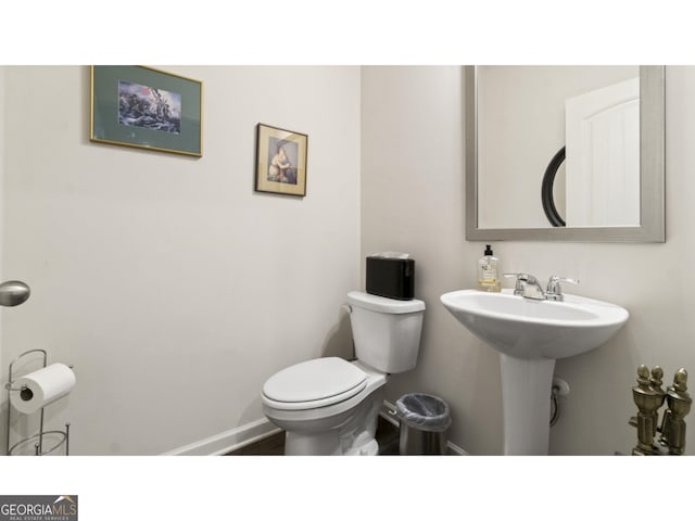 bathroom with toilet, baseboards, and a sink