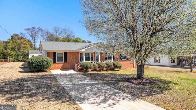 single story home featuring brick siding, concrete driveway, and a front yard