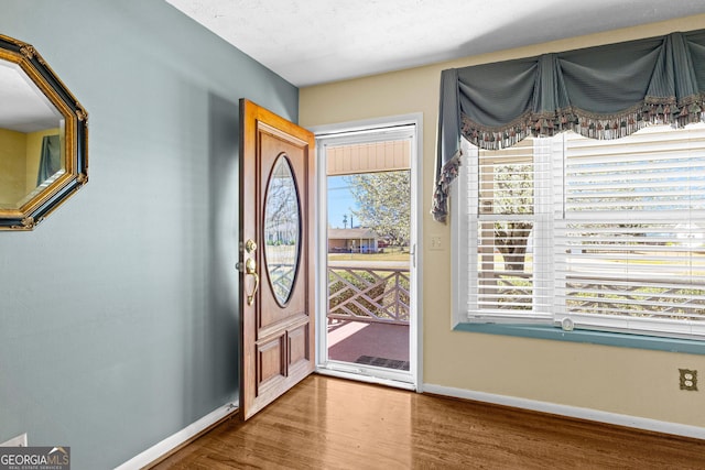 foyer featuring baseboards and wood finished floors