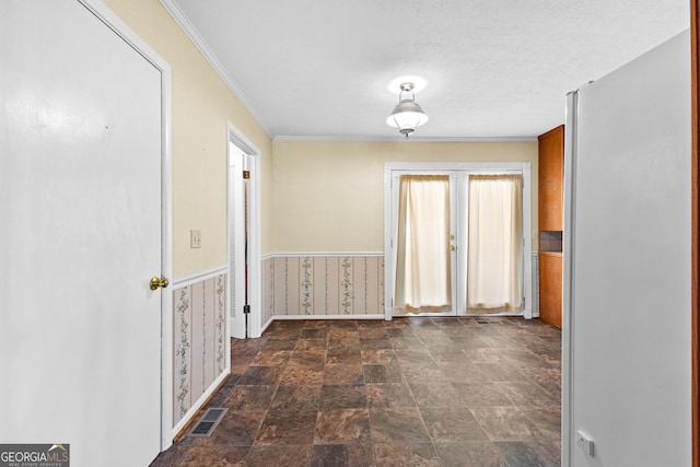 interior space with visible vents, ornamental molding, stone finish floor, a textured ceiling, and baseboards