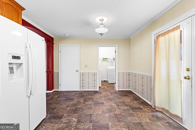 interior space featuring a wainscoted wall, ornamental molding, white fridge with ice dispenser, stone finish floor, and washer / clothes dryer