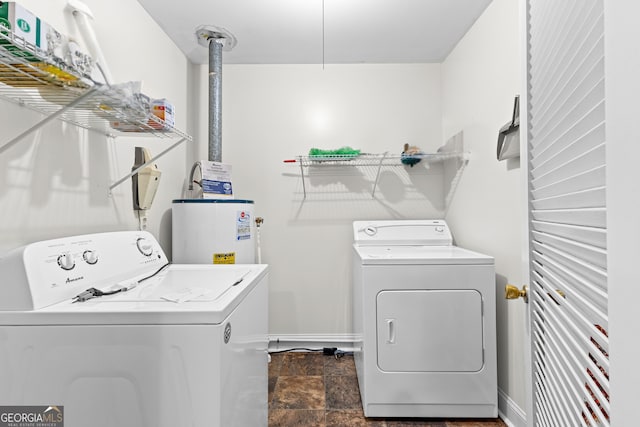 laundry area featuring washer and dryer, water heater, laundry area, and stone finish floor