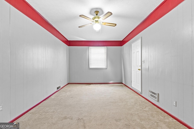 unfurnished room with wooden walls, visible vents, ceiling fan, and carpet