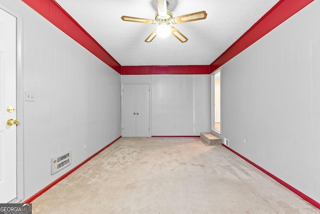 spare room featuring heating unit, carpet, and ceiling fan