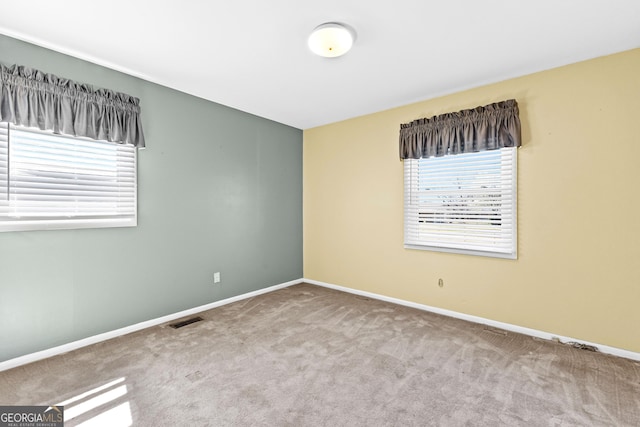 unfurnished room featuring visible vents, plenty of natural light, carpet, and baseboards