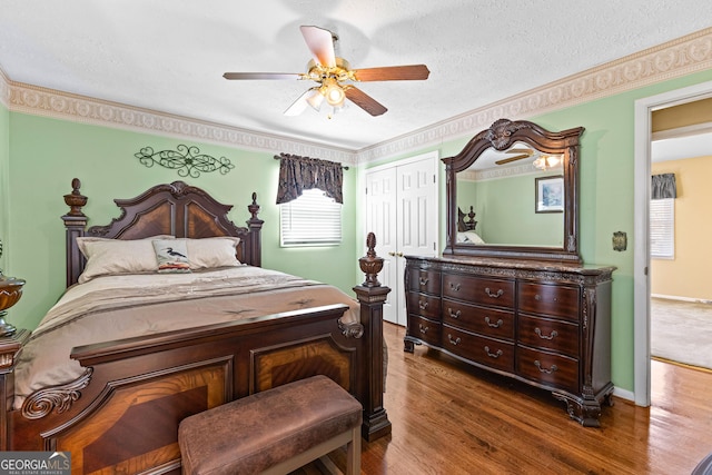 bedroom featuring a textured ceiling, wood finished floors, a closet, baseboards, and ceiling fan