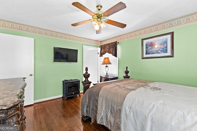 bedroom with dark wood-type flooring, ceiling fan, baseboards, a wood stove, and a textured ceiling