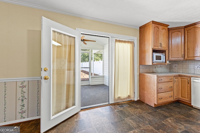 kitchen featuring white appliances, visible vents, light countertops, crown molding, and backsplash