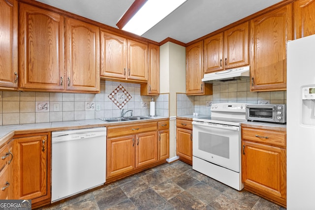 kitchen with stone finish floor, under cabinet range hood, a sink, white appliances, and a toaster