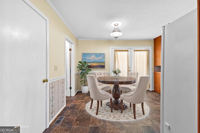 dining room with visible vents, a textured ceiling, ornamental molding, and stone finish floor