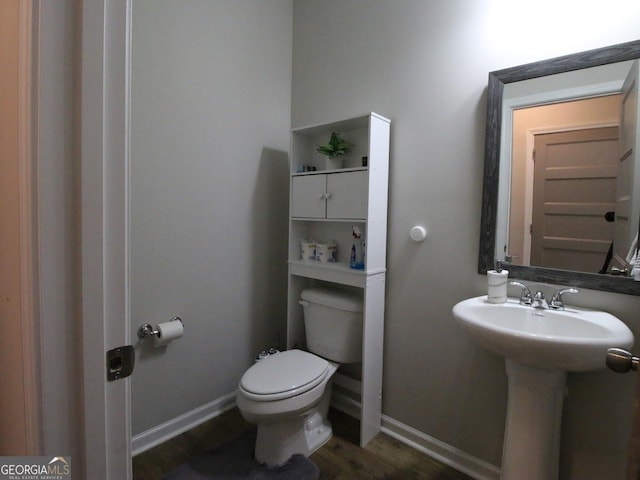 bathroom featuring a sink, baseboards, toilet, and wood finished floors