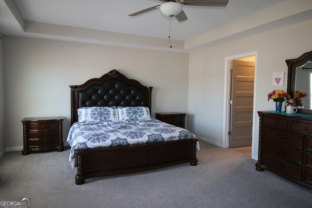 carpeted bedroom with a tray ceiling, baseboards, and ceiling fan