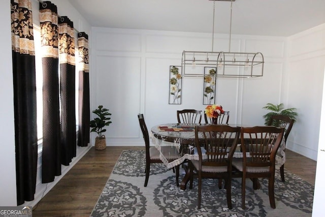 dining space featuring dark wood finished floors and a decorative wall