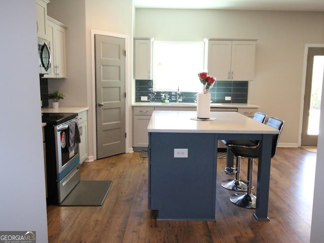 kitchen featuring tasteful backsplash, a kitchen island, a kitchen breakfast bar, stainless steel appliances, and a sink