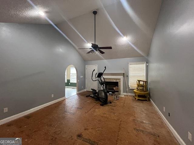 workout room with ceiling fan, a fireplace, baseboards, and high vaulted ceiling