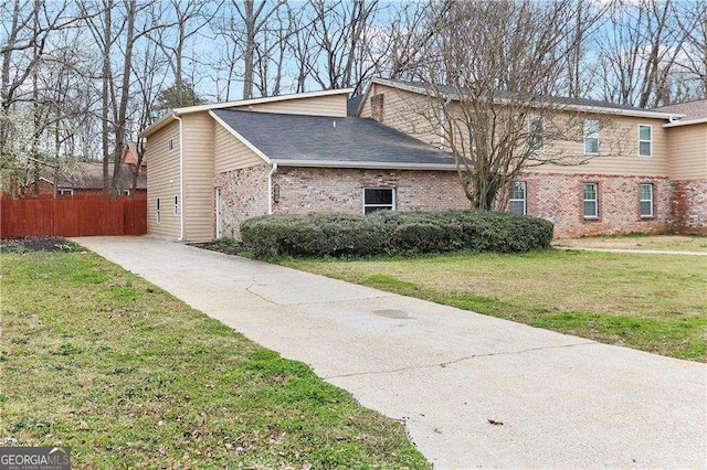 view of side of home featuring fence, a lawn, brick siding, and roof with shingles