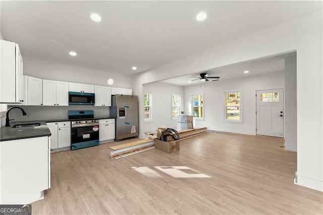 kitchen with stainless steel refrigerator with ice dispenser, a sink, dark countertops, black microwave, and stove