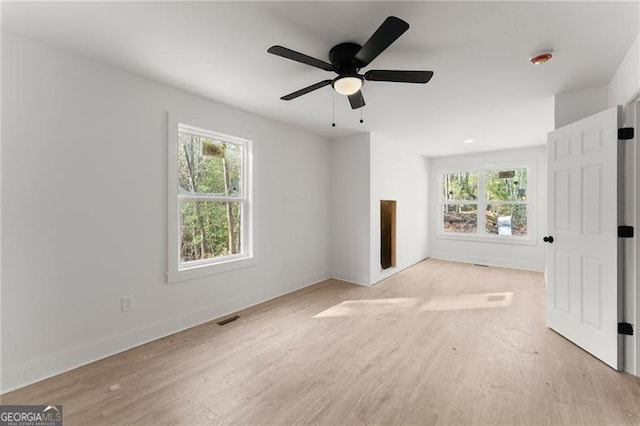 unfurnished living room featuring plenty of natural light, baseboards, visible vents, and light wood finished floors