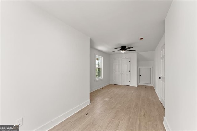 empty room featuring a ceiling fan, baseboards, and light wood finished floors