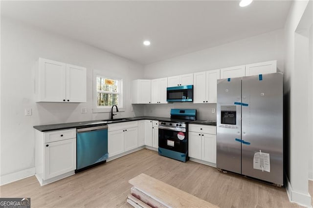 kitchen featuring a sink, dark countertops, white cabinets, and stainless steel appliances