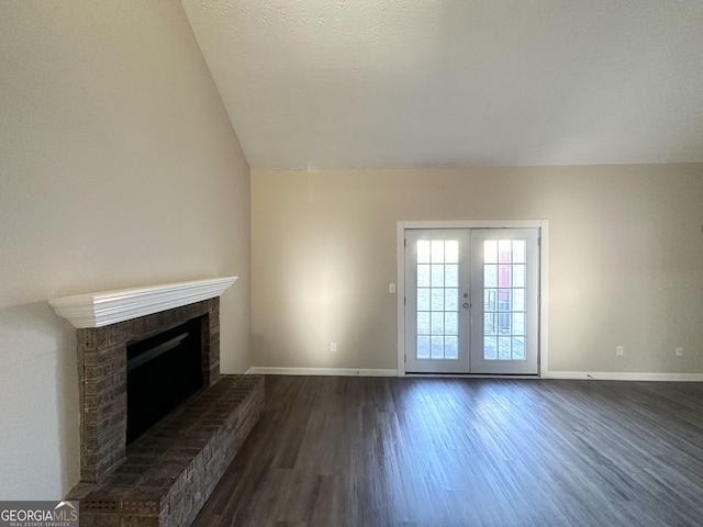 unfurnished living room featuring baseboards, dark wood finished floors, vaulted ceiling, french doors, and a brick fireplace