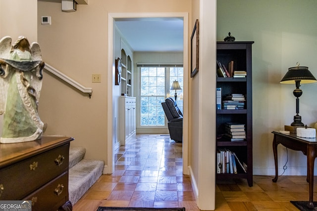 corridor with built in features, stairs, and baseboards