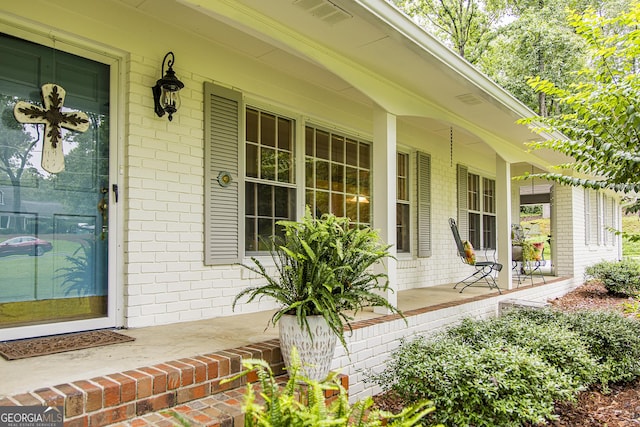 doorway to property with brick siding and covered porch