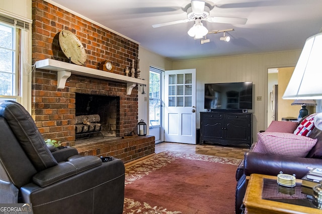 living room with a wealth of natural light, a brick fireplace, and ceiling fan