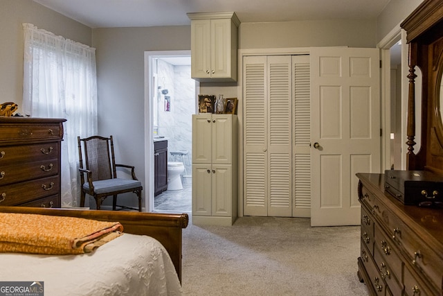 bedroom featuring a closet, light carpet, and ensuite bath