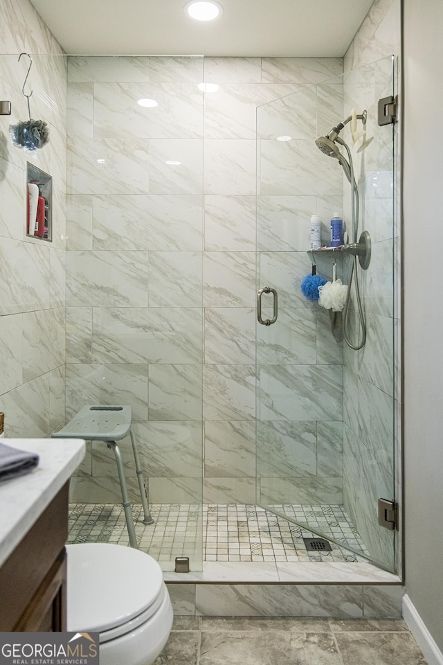 bathroom featuring a shower stall, toilet, and vanity