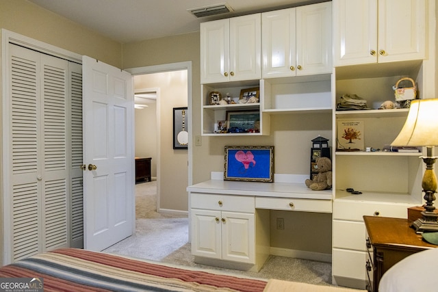 bedroom featuring visible vents, baseboards, light colored carpet, a closet, and built in study area