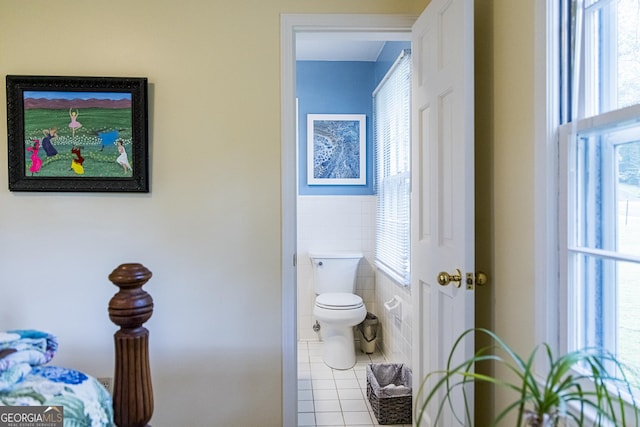 bathroom with tile patterned flooring, toilet, and tile walls