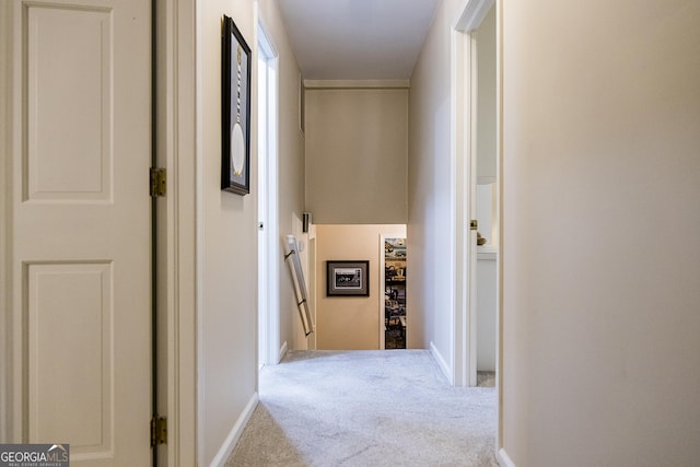 corridor with an upstairs landing, baseboards, and carpet