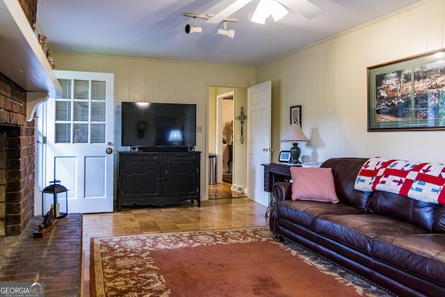 living area with a brick fireplace, ceiling fan, and ornamental molding