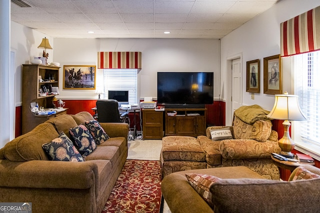 living room featuring a paneled ceiling, carpet, visible vents, and wainscoting