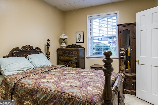 carpeted bedroom featuring a drop ceiling and multiple windows