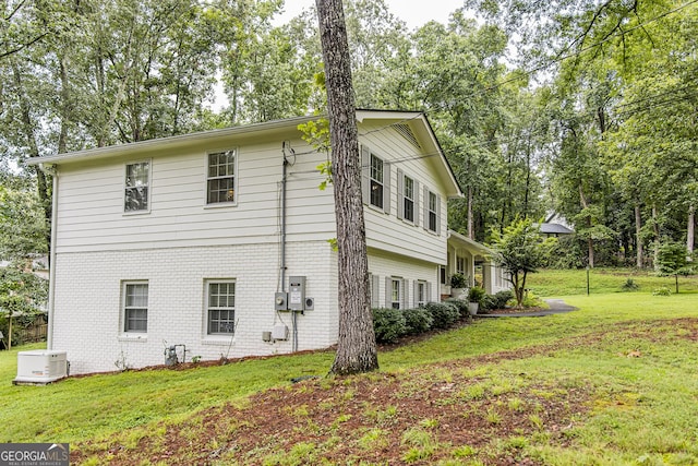 view of side of property featuring brick siding and a lawn