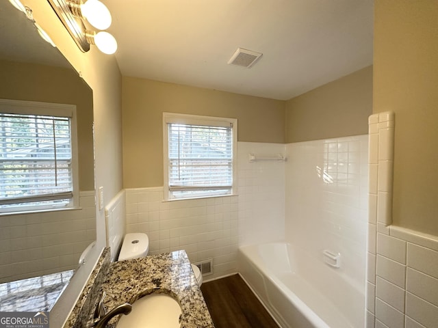 full bathroom with visible vents, wood finished floors, tile walls, and a wainscoted wall