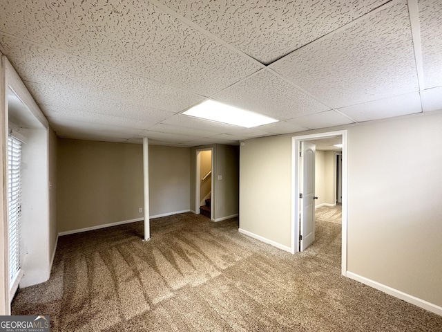 finished below grade area featuring stairs, carpet, baseboards, and a drop ceiling