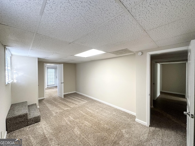 below grade area with carpet, baseboards, and a paneled ceiling