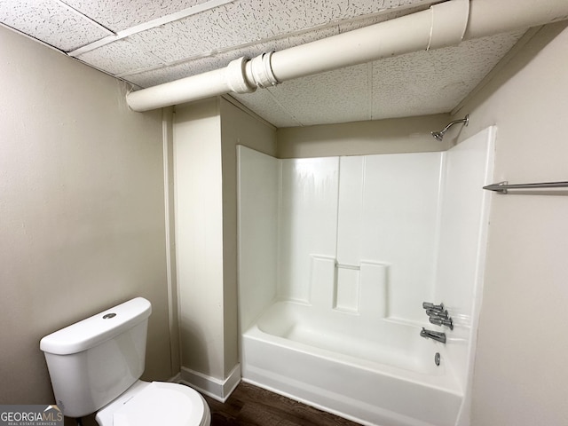 bathroom featuring toilet, a paneled ceiling, bathtub / shower combination, and wood finished floors