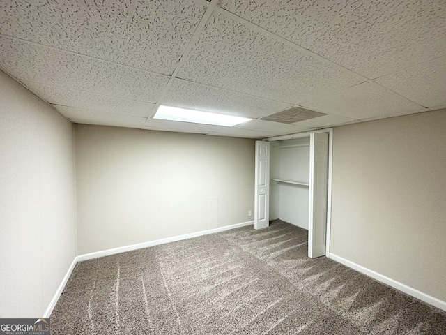 unfurnished bedroom featuring a paneled ceiling, baseboards, and carpet floors