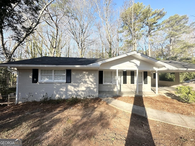 view of front facade featuring brick siding, covered porch, and driveway