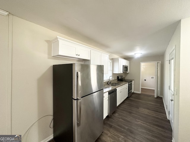 kitchen with dark wood-style flooring, white cabinets, appliances with stainless steel finishes, and a sink