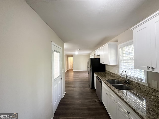 kitchen with dark wood finished floors, dark stone counters, a sink, appliances with stainless steel finishes, and white cabinetry