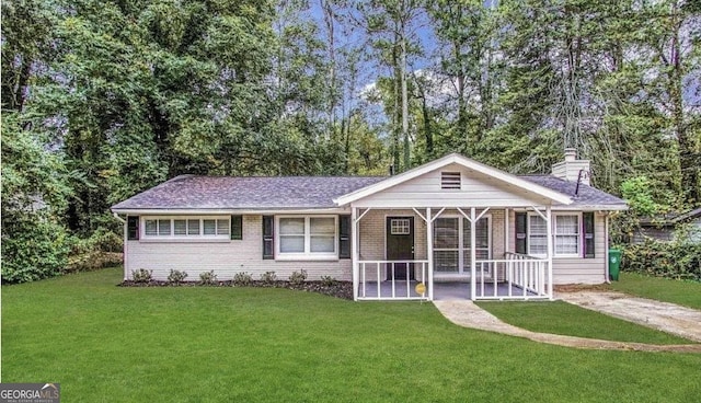 ranch-style house featuring brick siding, a chimney, covered porch, and a front lawn